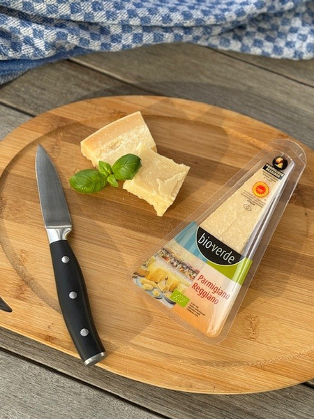 KI generiert: Käseplatte mit Parmigiano Reggiano, Messer, Basilikum und verpacktem Stück von "biovegan".