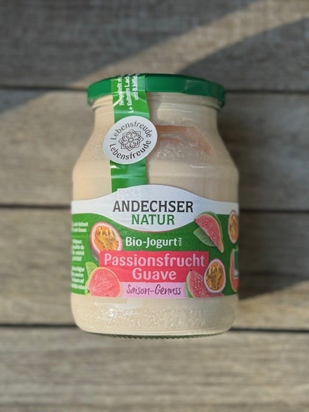 KI generiert: Das Bild zeigt ein frisch gebackenes Brotlaib auf einem Holzbrett, neben einem Brotmesser. Im Hintergrund ist ein blau-weiß kariertes Tuch zu sehen.