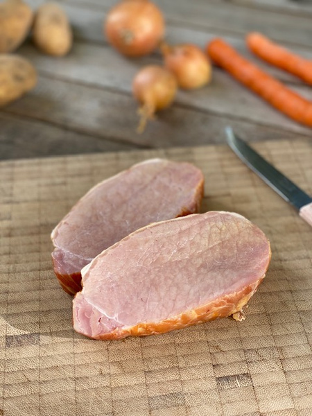 KI generiert: Das Bild zeigt ein frisch gebackenes Brotlaib auf einem Holzbrett, neben einem Brotmesser. Im Hintergrund ist ein blau-weiß kariertes Tuch zu sehen.
